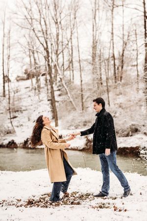 Couple playing and dancing together in a snow-covered woodland setting in Bridgeport, CT.