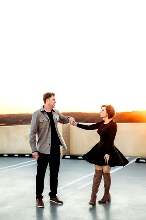 Playful couple dancing together on a rooftop at sunset in Branford, CT.