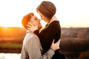 Couple sharing a tender moment against a warm sunset backdrop in Branford, CT.