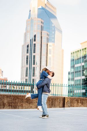 A couple shares a romantic moment on a rooftop with city skyscrapers in the background in New Haven, CT.