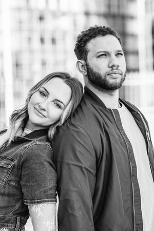 A couple poses together outdoors against an urban backdrop wearing casual denim outfits in New Haven, CT.