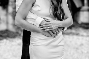 Black and white photo showing couple embracing in Bridgeport, CT, with focus on hands holding each other against a white dress.