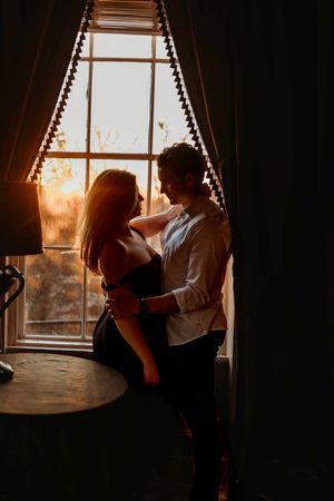 A silhouetted couple embraces by a window during golden hour sunset in Branford, CT.