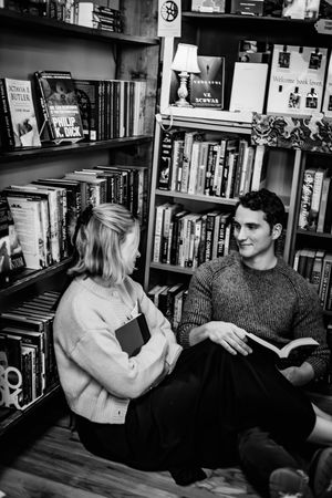 A romantic couple sits together in a cozy library surrounded by bookshelves  in Hamden, CT.
