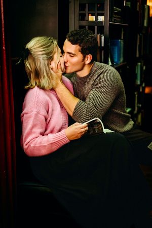 A couple embraces while sitting among bookshelves in a warm, atmospheric library setting in Hamden, CT.