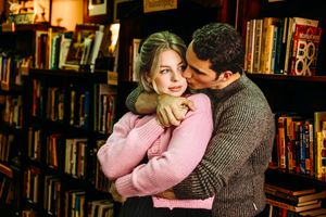 Two people share a tender moment between library shelves filled with books in Hamden, CT.