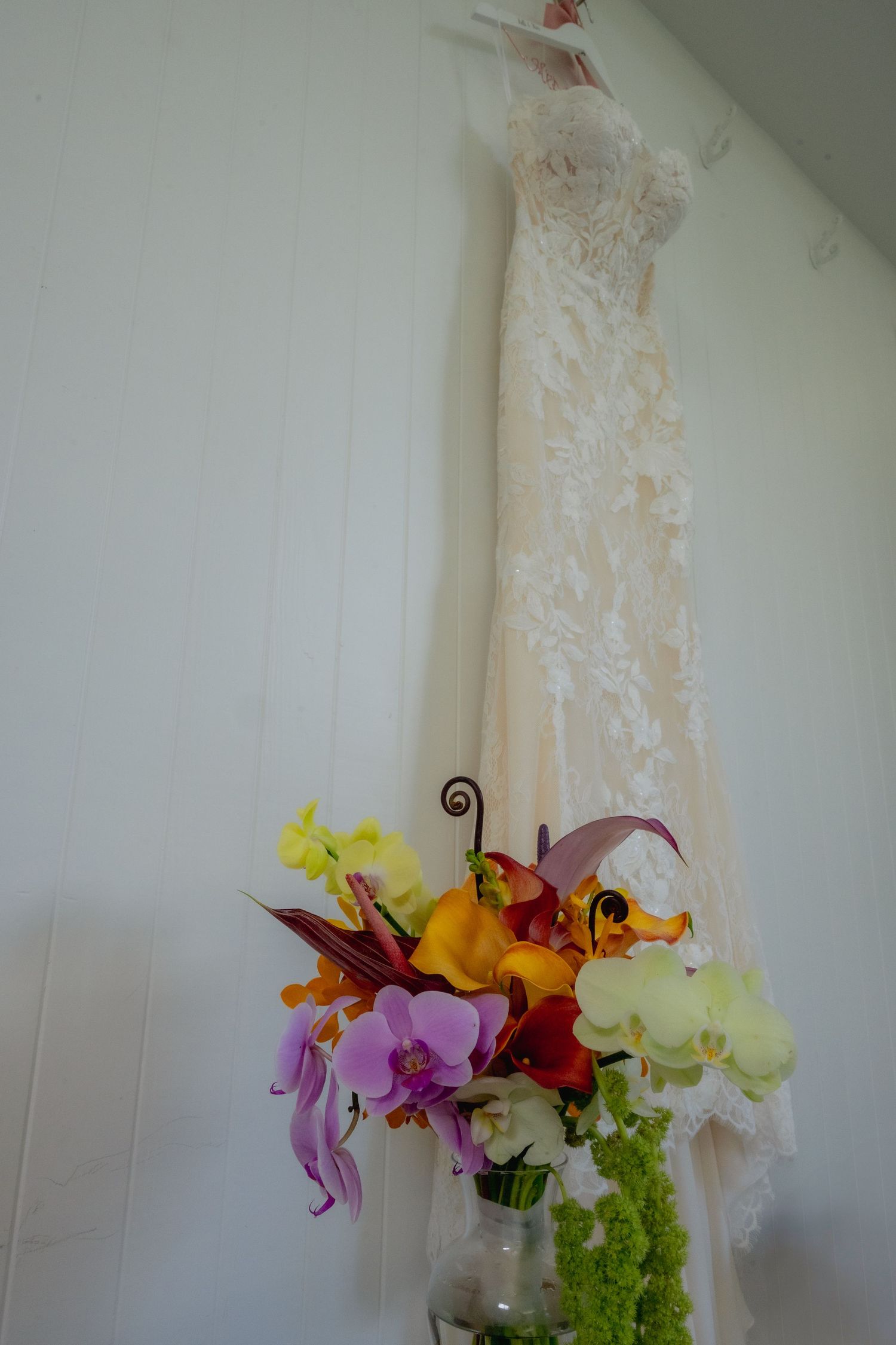 Oahu Wedding Photographer Studio 3511 Photography with close up of wedding bouquet with purple and yellow orchids. wedding dress hanging.