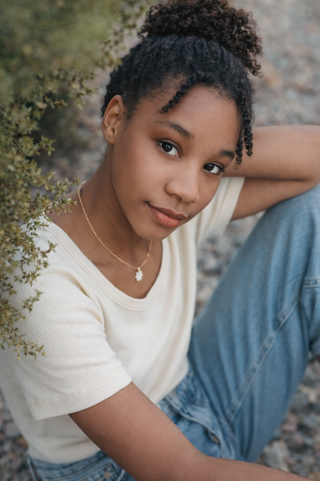 Portrait series in natural lighting showing someone wearing a white top and denim against a blurred outdoor background.