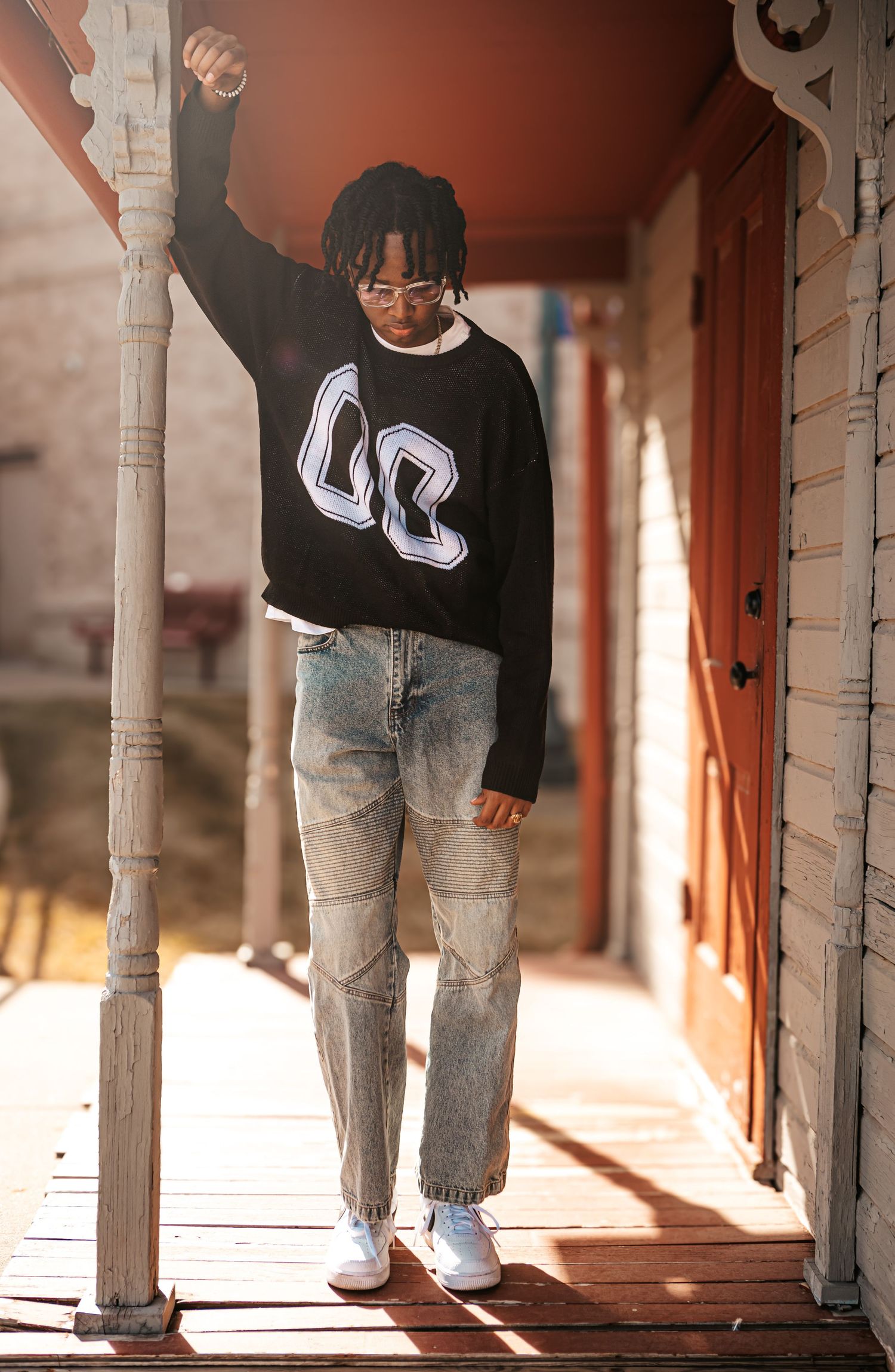 Stylish casual portrait on porch wearing 00 sweater and distressed jeans.