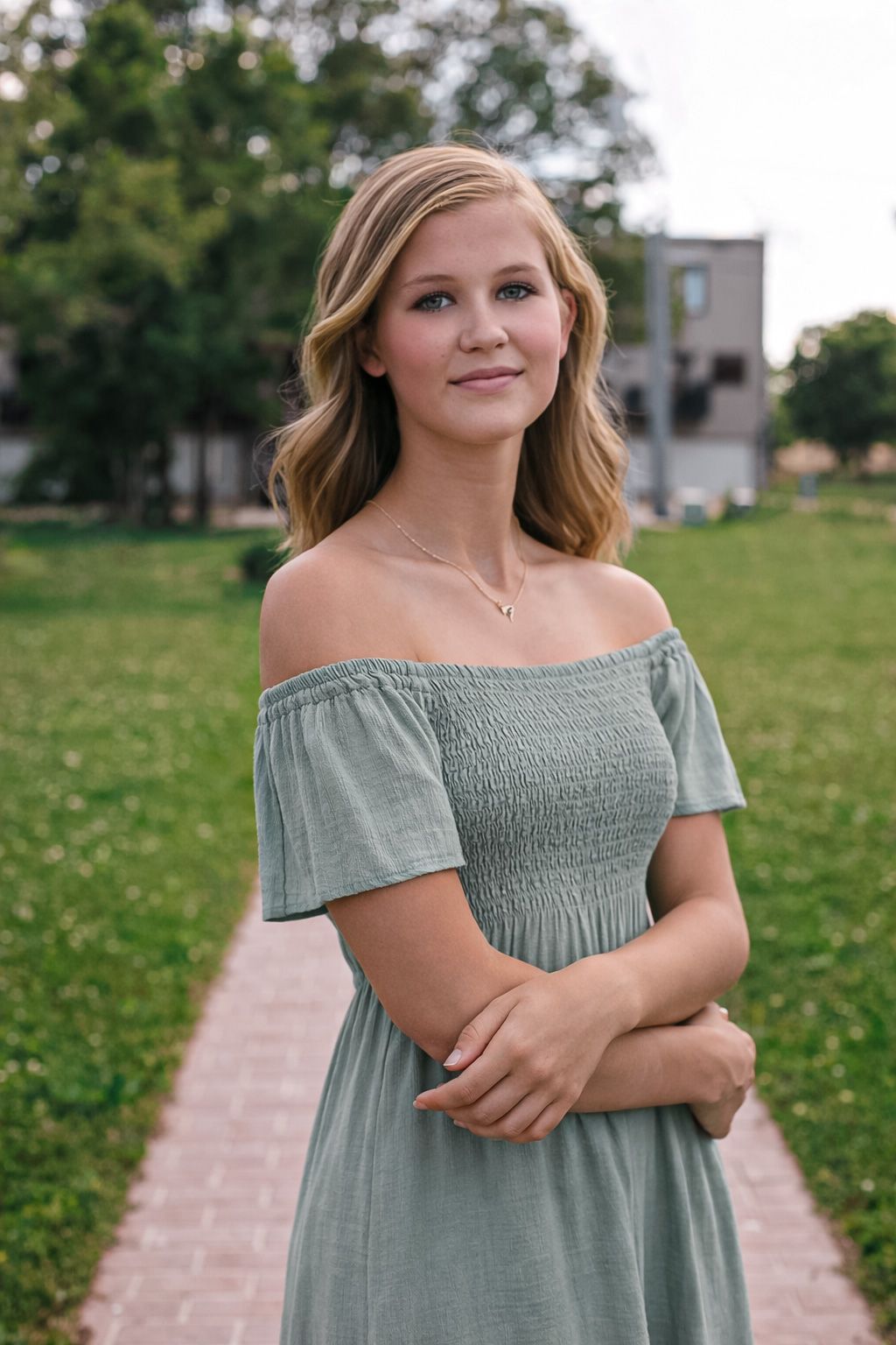 Outdoor portrait poses on a brick path with green grass and buildings in the background.
