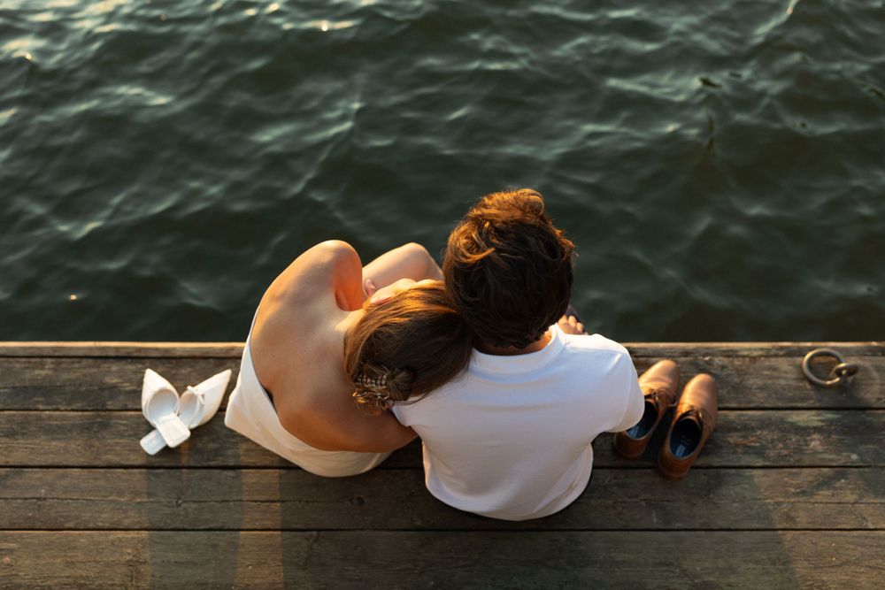 Intimate moment shared on wooden dock overlooking dark waters.