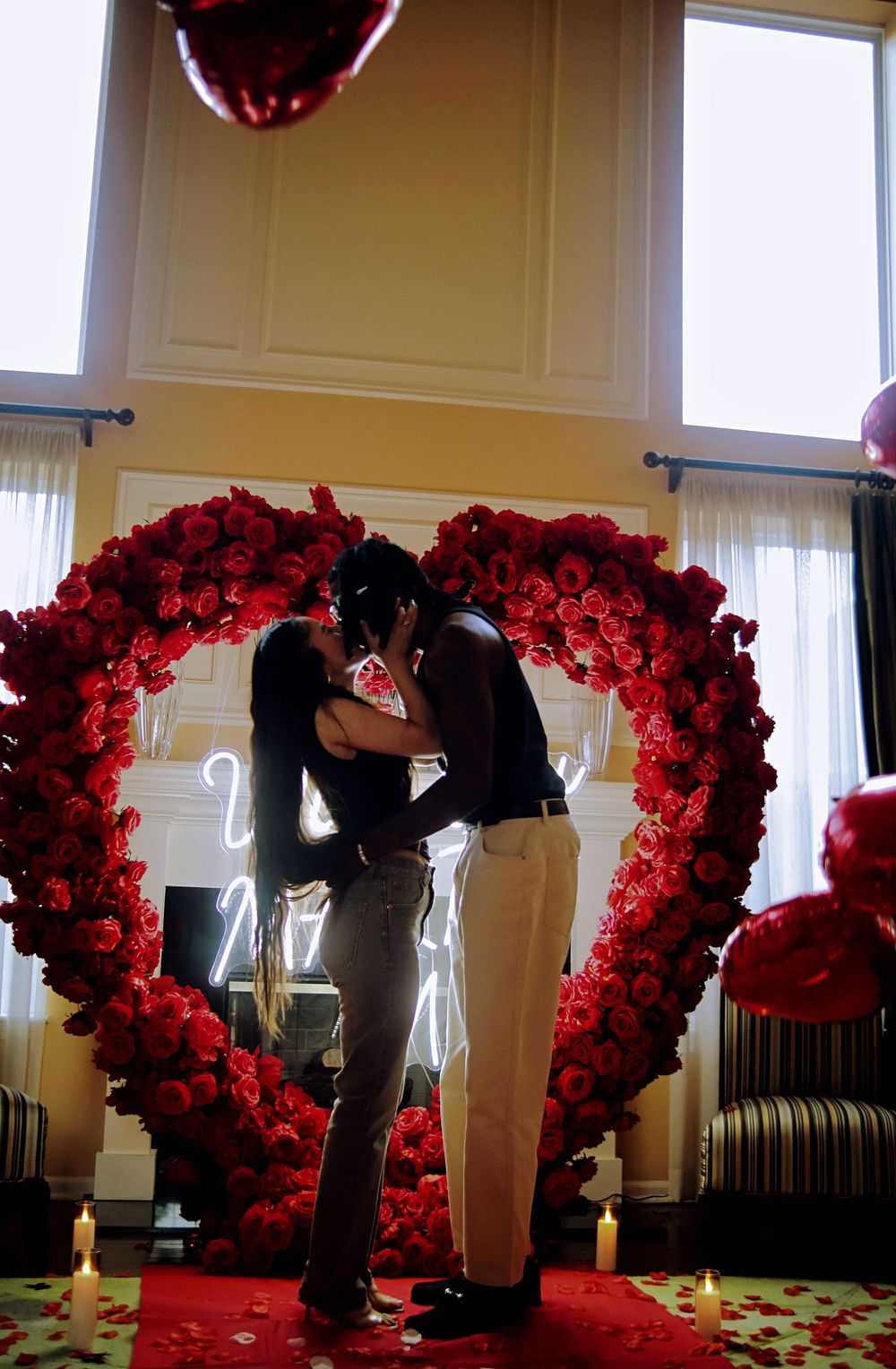 A series of red rose floral arches arranged in a line create a romantic wedding ceremony backdrop.