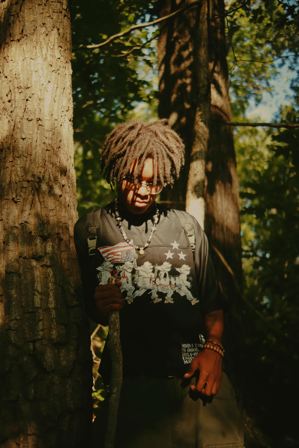 A series of moody forest portraits showing someone in dark clothing against sunlit trees in a natural outdoor setting.