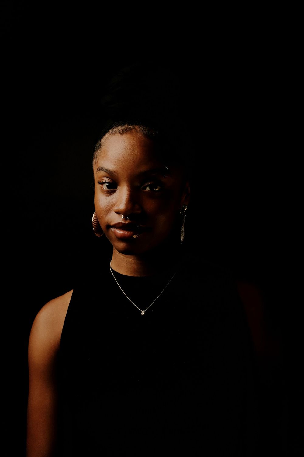 A series of dark, moody portrait photographs against a black background with dramatic lighting and shadows.