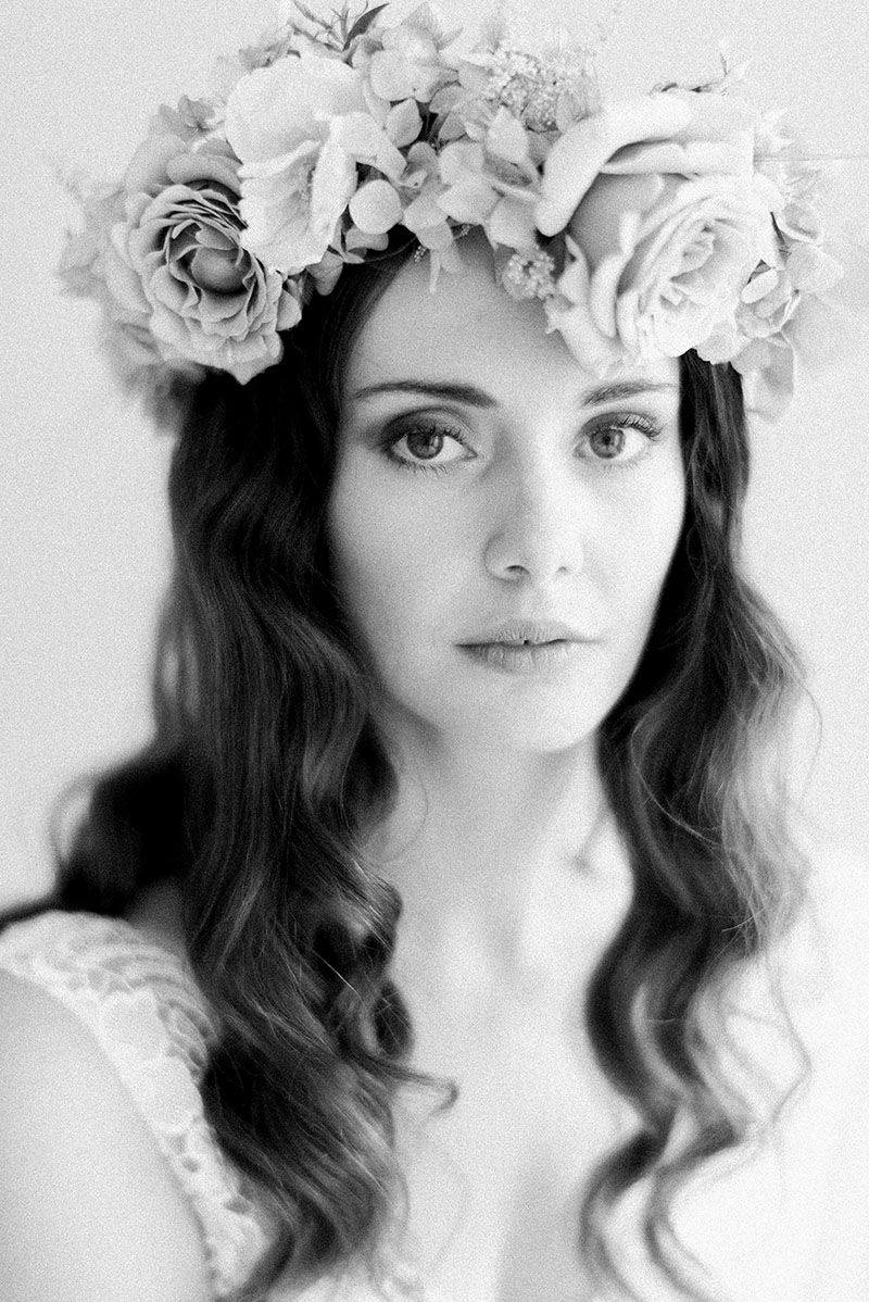 Black and white portrait of a bride wearing a floral crown with roses and wavy hair.