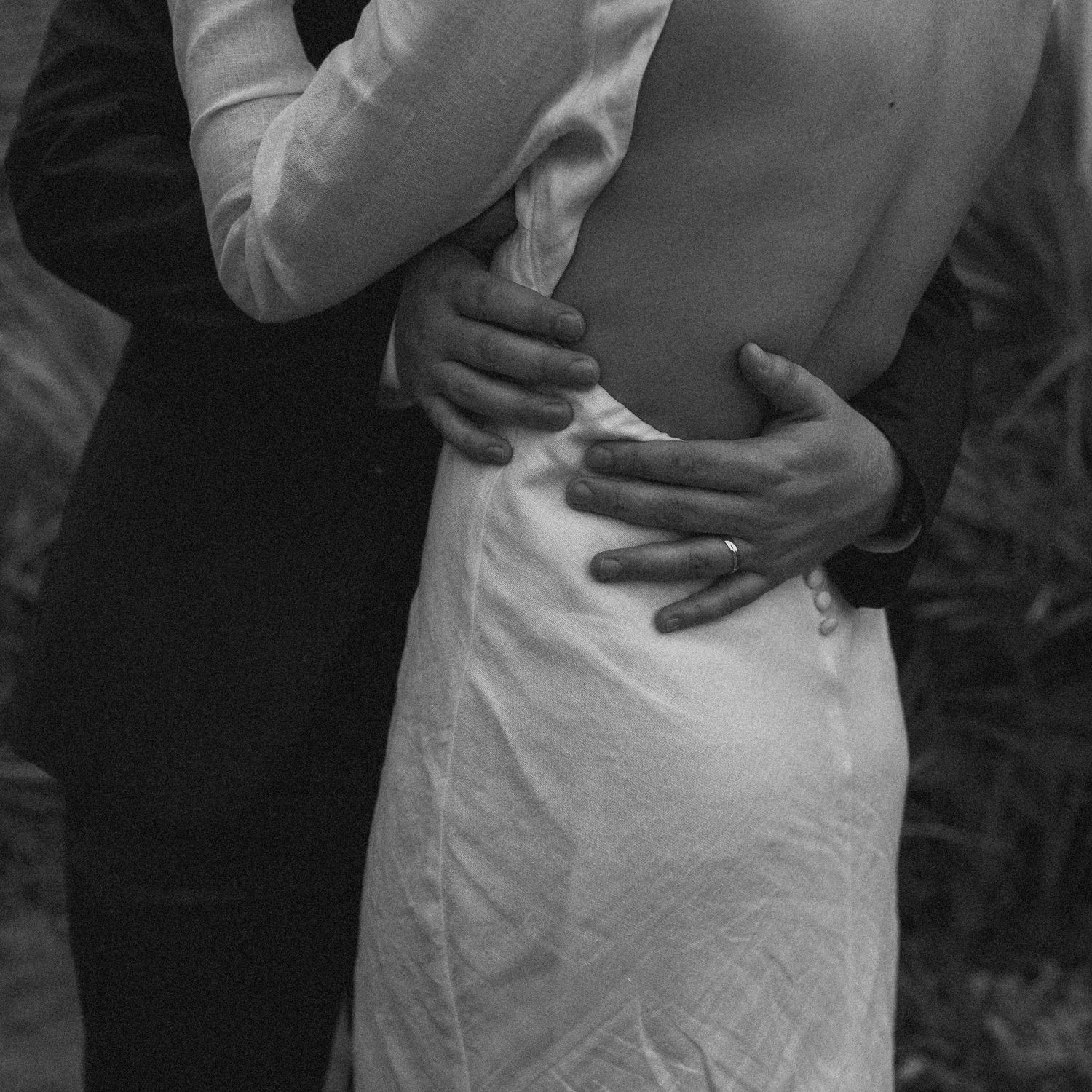 Black and white close-up of couple embracing in formal attire.