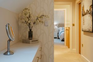 Elegant hallway with decorative mirror, vase of white flowers, and a glimpse into a bedroom. Interior design photography in Surrey.