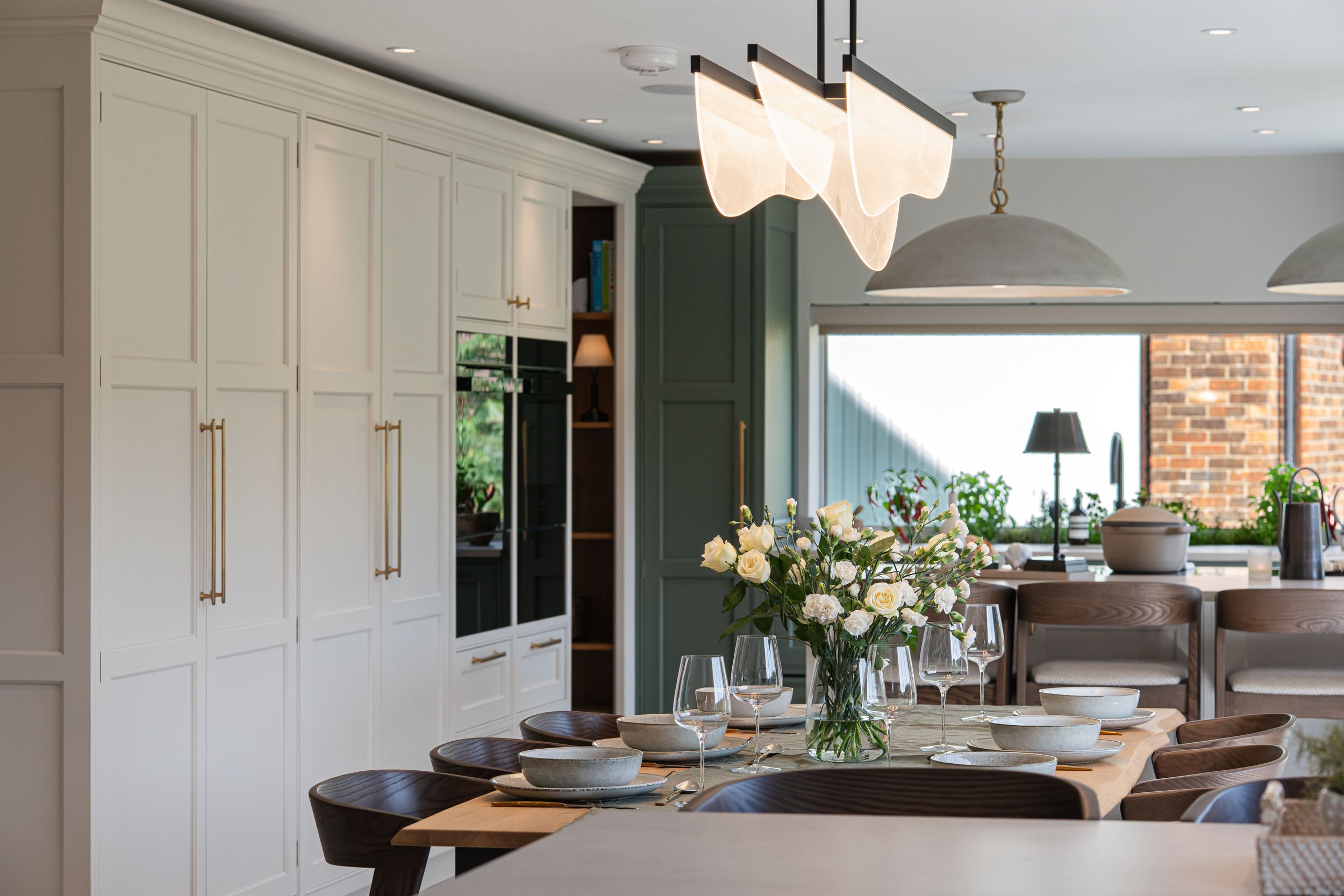 Modern open concept kitchen with white cabinets, dark countertops, and pendant lighting features a sleek minimalist design.