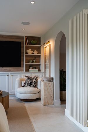 Modern living room with curved white walls, built-in shelving, and plush circular seating area on beige carpet.