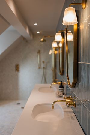 Elegant bathroom vanity with white countertops, brass fixtures, and wall-mounted sconce lighting.