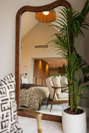 Contemporary dining area with rustic wood mirror, white pendant lamps, and tropical plants in white planters.