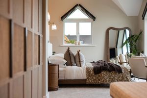 Minimalist attic bedroom with white walls, sloped ceiling, and natural light streaming through window.