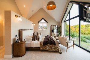 Modern attic bedroom with sloped ceiling, large windows, and natural light showcasing contemporary interior design.