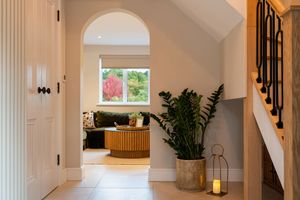 Bright hallway with white walls, hardwood floors, and arched doorway leading to interior spaces.
