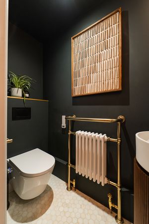 Contemporary powder room featuring black walls, wooden slat details, and gold fixtures with vessel sink.
