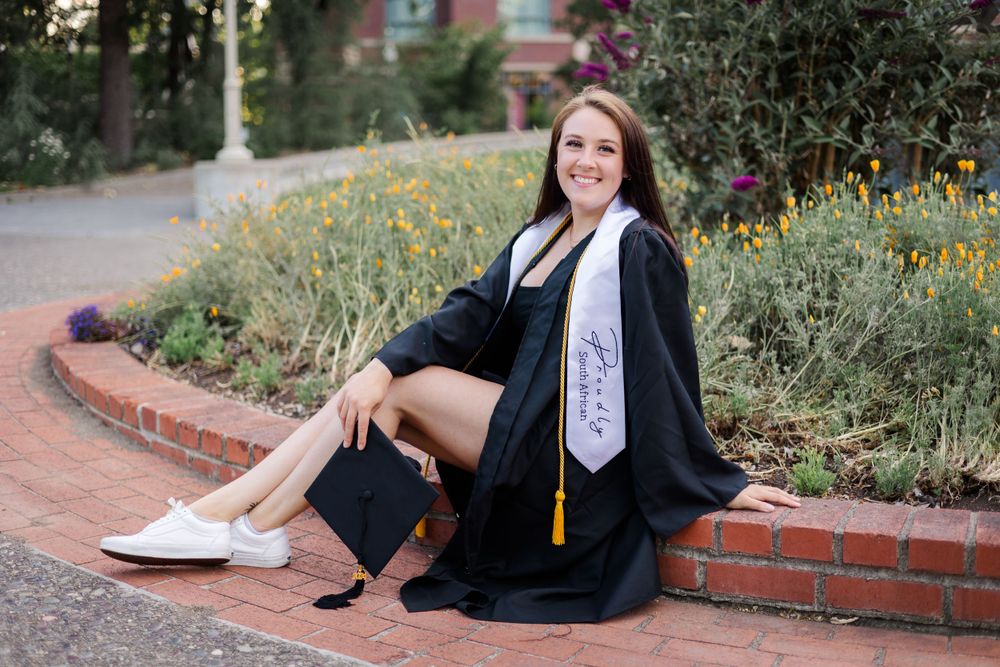 santa rosa junior college SRJC graduate, college senior. senior photos in Sonoma County, California. sitting near flowers in cap and gown