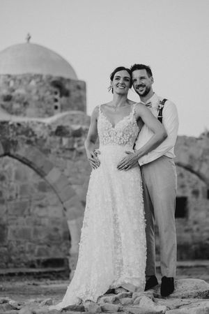 A romantic black and white wedding photo series featuring a couple embracing against a stone wall backdrop.