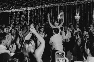 Black and white photo of a crowded dance floor with people dancing under string lights at a nighttime celebration.