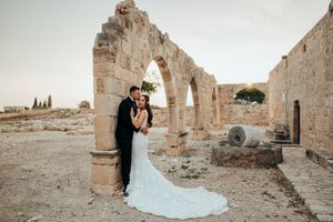 A romantic wedding photo captured at ancient stone ruins with dramatic archways and architectural details.