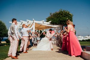 Collage of outdoor wedding ceremony moments with guests gathered in coral and neutral attire on a sunny day.