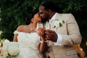 A romantic wedding couple shares intimate moments in a garden setting wearing cream and white formal attire.