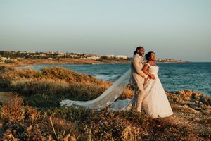 Romantic coastal wedding photoshoot with couple by the ocean during golden hour at a scenic Mediterranean beach.
