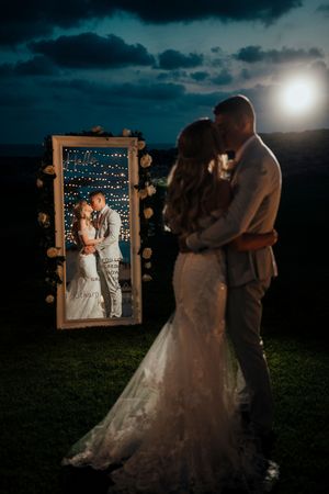 A romantic moonlit photo session featuring a couple posing in front of an illuminated picture frame under dark skies.