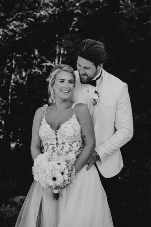 Black and white wedding portraits showing romantic moments between newlyweds in a forest setting.