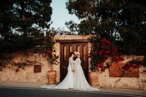 Outdoor wedding ceremony setup with rustic wooden decor and floral arrangements against stone walls at sunset.