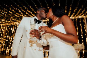 Newlyweds share their first dance together under romantic twinkle lights at an evening wedding reception.