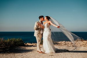 A romantic seaside wedding portrait with the ocean and blue sky creating a stunning backdrop.