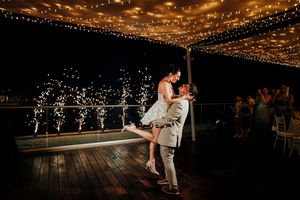 Romantic dance scene at a wedding reception under twinkling string lights on a dark wooden floor.