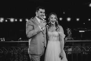 A happy couple shares a romantic dance moment at their outdoor wedding reception under string lights.
