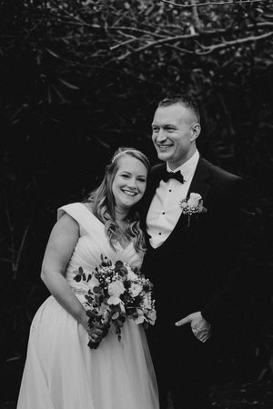 A black and white photo series of a bride and groom sharing candid laughing moments during their wedding photoshoot.