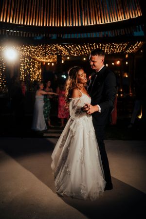 First dance under romantic string lights at evening wedding reception.
