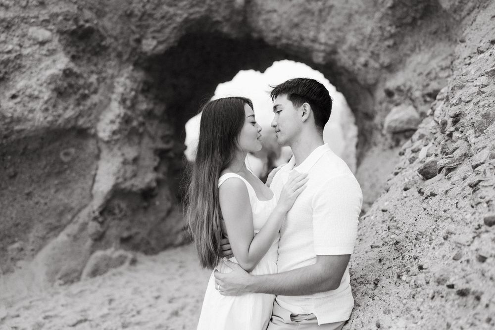 A romantic black and white photo series of a couple sharing intimate moments against a textured stone wall backdrop.