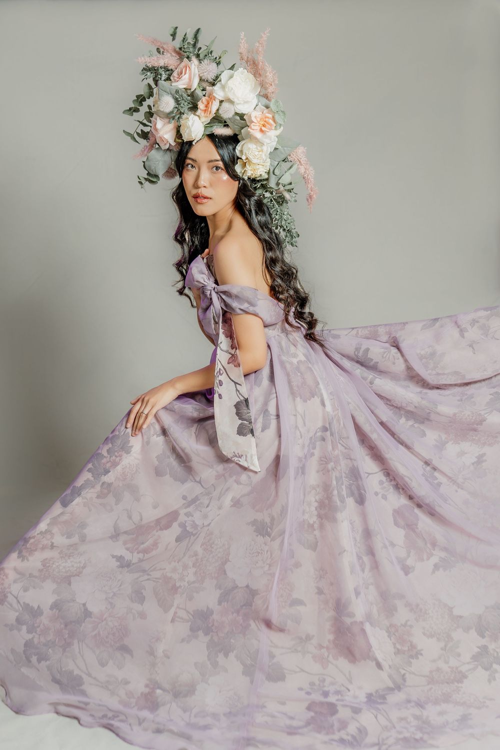 Ethereal portrait featuring a flowing lavender gown and an elaborate floral crown with white and peach blooms.