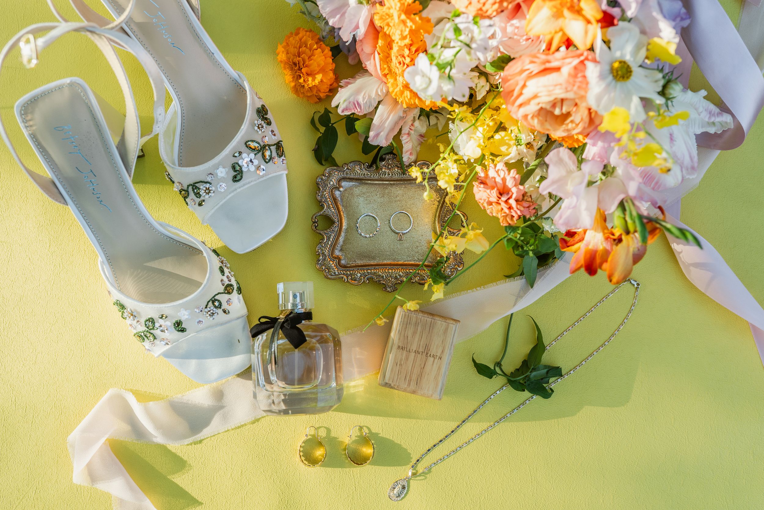 Delicate teacups filled with colorful flowers arranged in a row on a light yellow background.