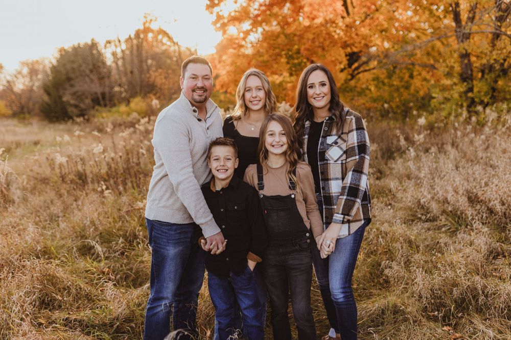 Family photo session in autumn field with golden foliage.