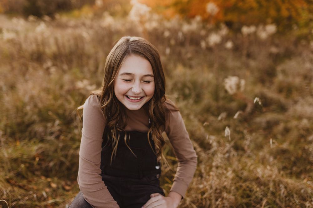 Portrait session in autumn field with warm sunlight and tall grass.